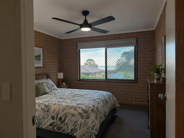Bedroom with brick walls and a ceiling fan above a bed in Toukley