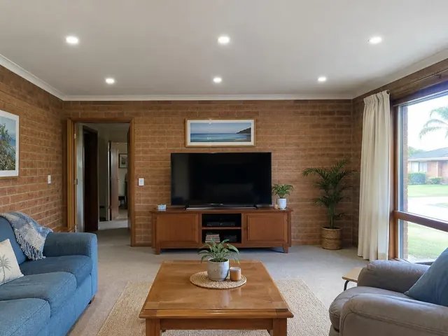 Living room with recessed downlights, brick walls, TV and large window in Noraville